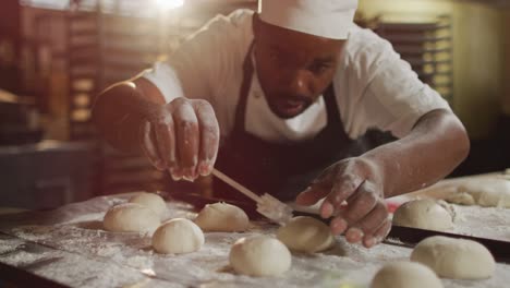 Animation-of-focused-african-american-male-baker-preparing-rolls
