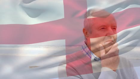 Animation-of-flag-of-england-over-thoughtful-senior-caucasian-man-on-beach
