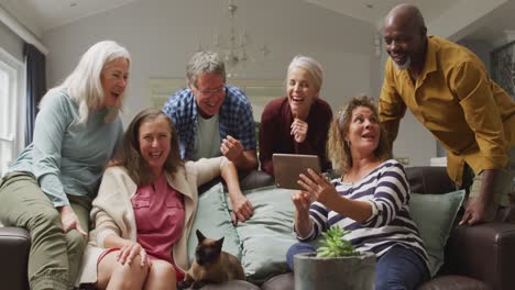 Animation-of-happy-diverse-female-and-male-senior-friends-using-tablet-at-home