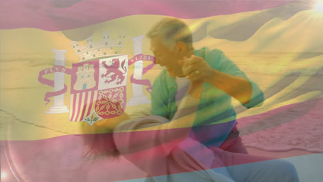 Animation-Der-Flagge-Spaniens-über-Einem-Glücklichen-älteren-Kaukasischen-Paar,-Das-Am-Strand-Tanzt