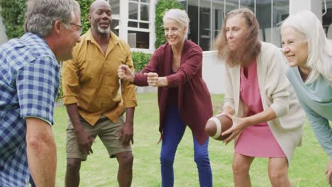 Animation-of-happy-diverse-female-and-male-senior-friends-playing-american-football-in-garden