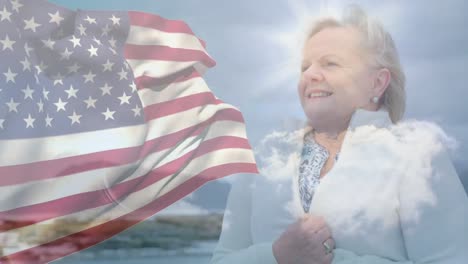 Animation-of-flag-of-united-states-of-america-over-happy-senior-caucasian-woman-on-beach