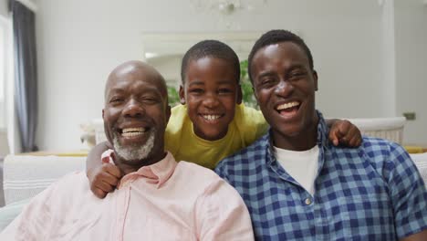 Happy-african-american-grandfather,-father-and-son-embracing-on-sofa