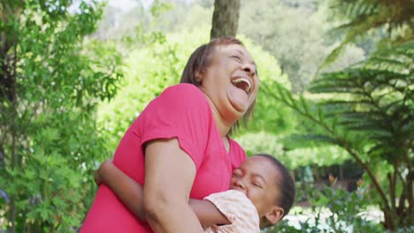 Feliz-Abuela-Y-Nieta-Afroamericana-Abrazándose-Y-Divirtiéndose-En-El-Jardín