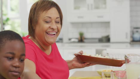 Animation-of-happy-african-american-grandmother-and-grandson-eating-lunch-at-home