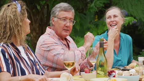 Animation-of-happy-caucasian-senior-female-and-male-friends-talking-at-lunch-in-garden