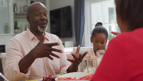Feliz-Abuelo-Afroamericano-Hablando,-Almorzando-Con-La-Familia-En-Casa