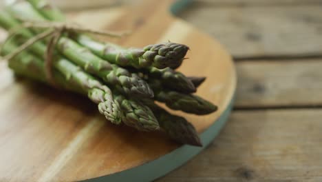 Video-of-close-up-of-fresh-asparagus-bundles-on-wooden-board-background