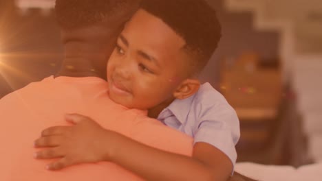 Animation-of-lights-over-happy-african-american-father-and-son-hugging-at-home