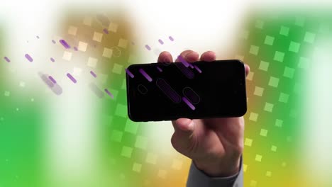 Animation-of-purple-shapes-falling-over-hand-of-caucasian-man-holding-smartphone-with-copy-space