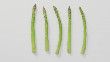 Video-of-close-up-of-five-fresh-asparagus-stalks-over-white-background