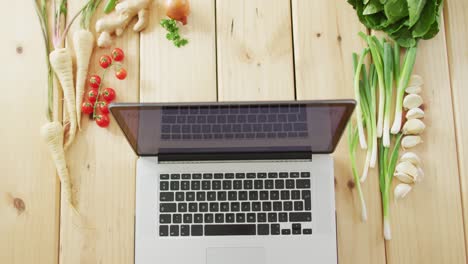 Video-of-fresh-vegetables-around-laptop-on-wooden-background