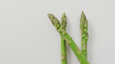 Video-of-close-up-of-fresh-asparagus-with-copy-space-over-white-background