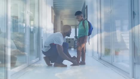 Animation-of-lights-over-happy-african-american-father-tying-shoe-to-son