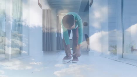 Animation-of-clouds-over-african-american-boy-tying-shoe