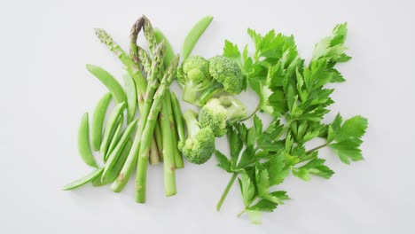 Video-of-close-up-of-fresh-green-vegetables-on-white-background
