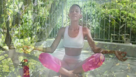 Animation-Von-Blättern-über-Einer-Afroamerikanischen-Frau,-Die-Yoga-Praktiziert-Und-Meditiert
