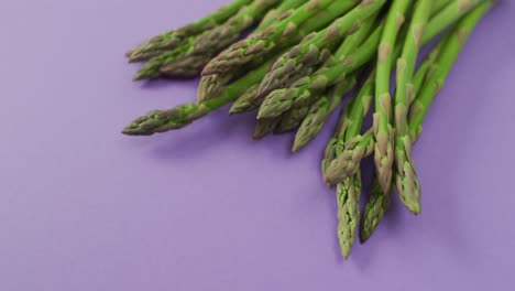 Video-of-close-up-of-fresh-asparagus-with-copy-space-over-lilac-background