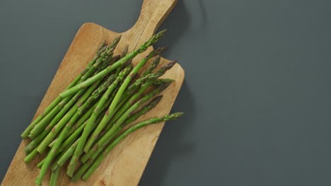 Video-of-asparagus-on-wooden-chopping-board-over-grey-background