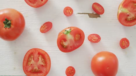 Vídeo-De-Tomates-Rojos-Frescos,-Cortados-A-La-Mitad-Y-Enteros,-Sobre-Fondo-Rústico-Blanco