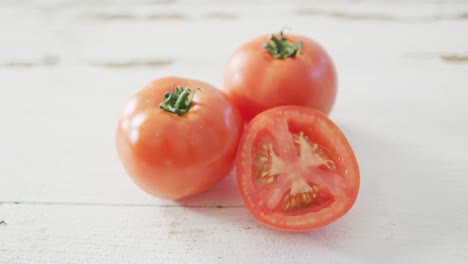 Video-of-halved-and-whole-fresh-red-tomatoes-on-white-rustic-background