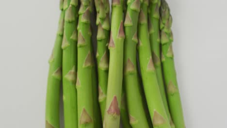 Video-of-close-up-of-fresh-asparagus-over-white-background