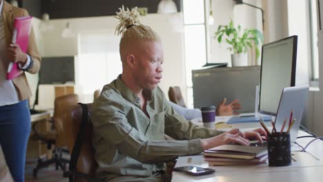 Albino-african-american-businessman-using-laptop-in-creative-office
