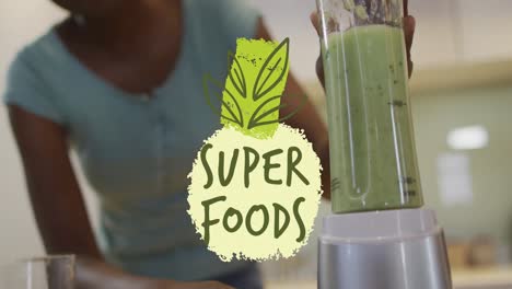 Animation-of-super-foods-text-over-happy-african-american-woman-making-healthy-drink
