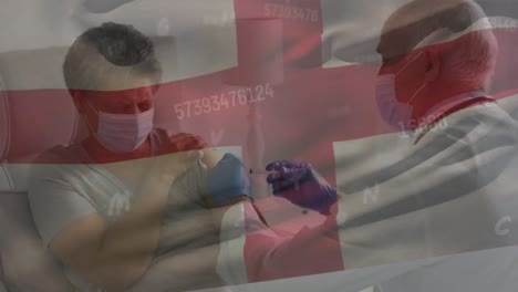 Animation-of-numbers-and-england-flag-over-diverse-male-doctor-vaccinating-senior-woman