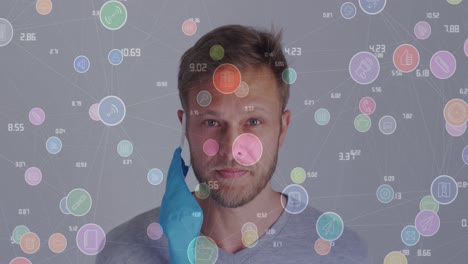 Animation-of-network-of-connections-with-icons-over-caucasian-man-taking-off-face-mask
