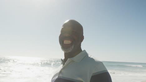 Portrait-of-smiling-senior-african-american-man-on-sunny-beach