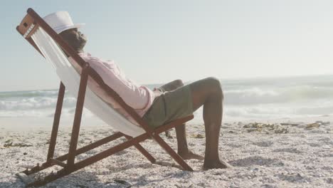 Senior-african-american-man-lying-on-sunbed-on-sunny-beach