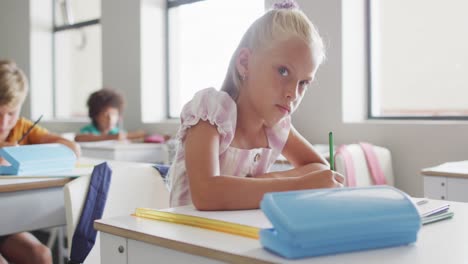 Video-of-focused-caucasian-girl-sitting-at-desk-in-classsroom