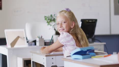 Video-Eines-Glücklichen-Kaukasischen-Mädchens,-Das-Im-Klassenzimmer-Am-Schreibtisch-Sitzt