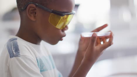 Video-Eines-Glücklichen-Afroamerikanischen-Jungen,-Der-Während-Des-Chemieunterrichts-Eine-Brille-Trägt-Und-Reagenz-In-Der-Hand-Hält