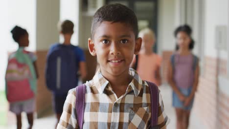 Video-of-happy-biracial-boy-standing-at-school-corridor