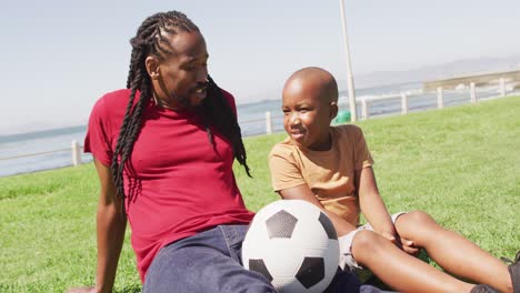Video-Eines-Glücklichen-Afroamerikanischen-Vaters-Und-Sohnes,-Die-Sich-Draußen-Mit-Dem-Ball-Amüsieren