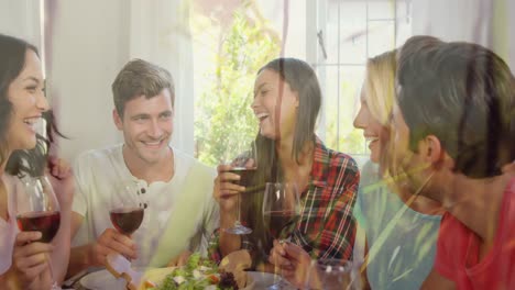 Animation-of-grass-over-caucasian-female-and-male-friends-drinking-wine-and-talking-at-home