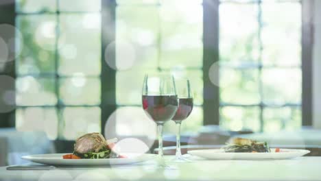 Animation-of-bokeh-over-table-with-meal-and-glasses-with-red-wine