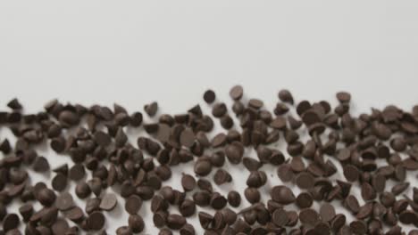 Video-of-close-up-of-multiple-chocolate-chip-with-copy-space-over-white-background