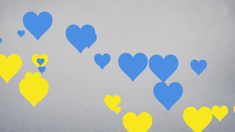 Animation-of-blue-and-yellow-hearts-floating-over-grey-background