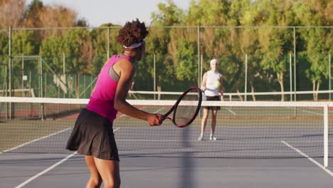 Video-of-back-of-african-american-female-tennis-player-holding-racket-and-hitting-ball