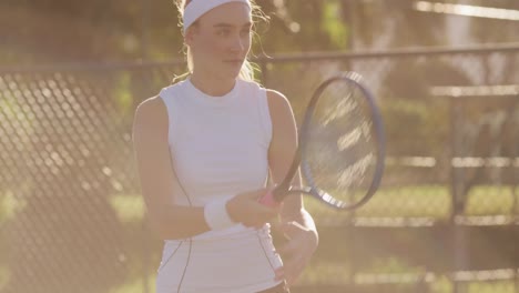 Video-of-focused-caucasian-female-tennis-player-holding-racket-and-hitting-ball