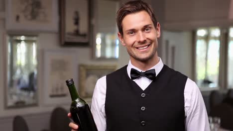 Handsome-waiter-holding-a-bottle-of-red-wine