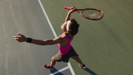 Video-Der-Draufsicht-Einer-Fokussierten-Afroamerikanischen-Tennisspielerin,-Die-Einen-Schläger-Hält-Und-Den-Ball-Schlägt