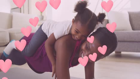 Animation-of-hearts-over-african-american-mother-with-daughter-exercising-and-smiling