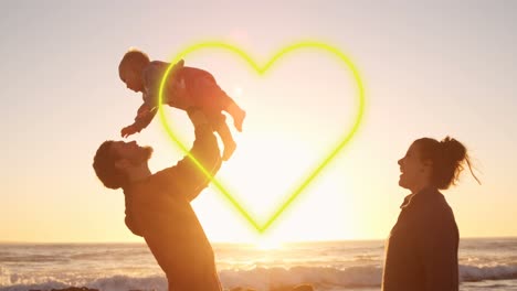 Animation-of-heart-over-happy-caucasian-parents-with-baby-at-beach