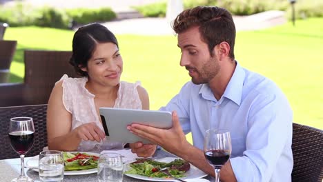 Couple-looking-at-tablet-over-lunch