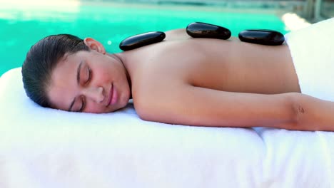 Friedliche-Brünette-Bekommt-Eine-Hot-Stone-Massage-Am-Pool