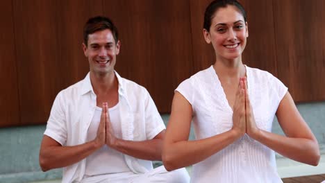 Smiling-couple-in-white-sitting-in-lotus-pose-with-hands-together